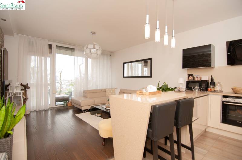 Living room in a two-room apartment with a sofa and wooden decor flooring.