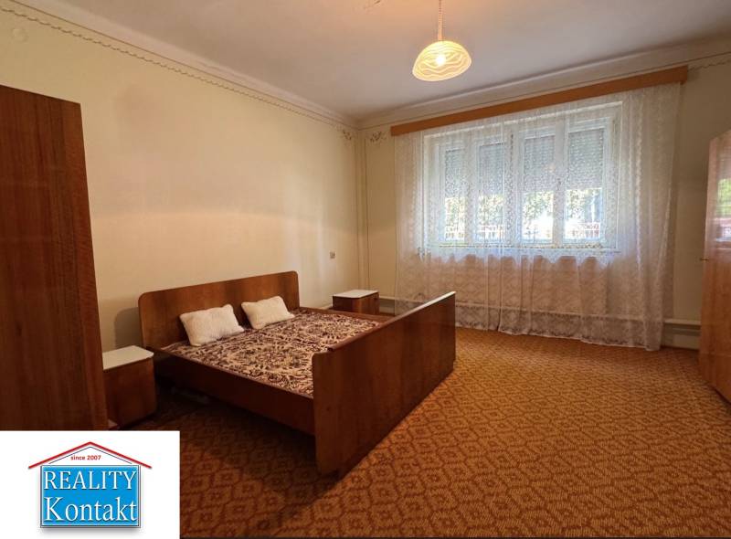 Bed with armchair and nightstands in a home bedroom with carpet.