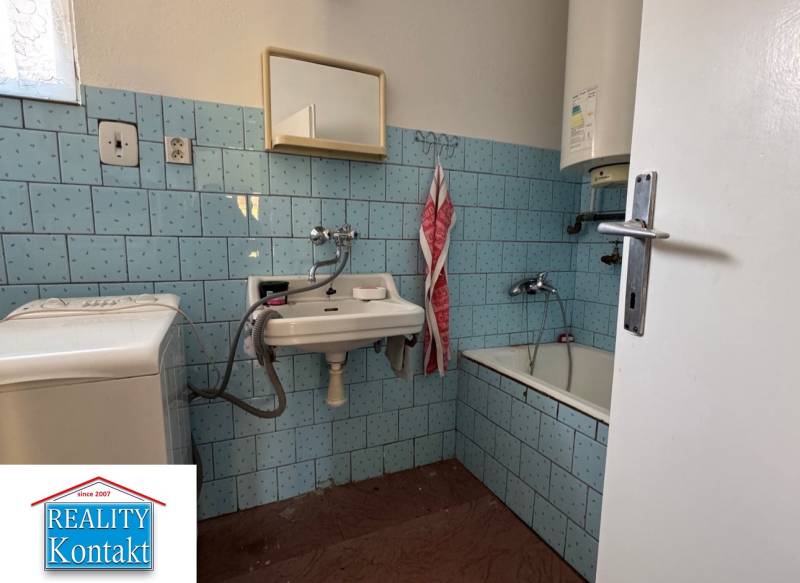A bathroom in a family house with blue tiles and a bathtub.
