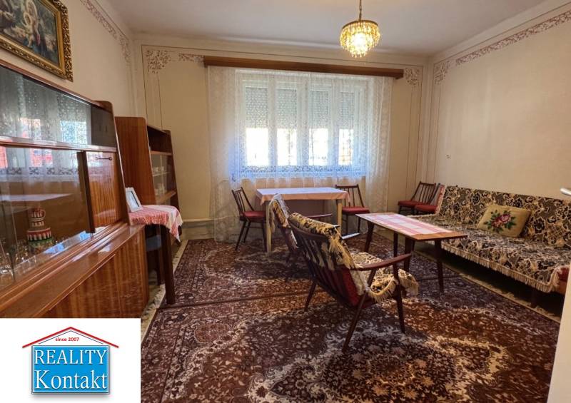 Living room in a family house with a carpet, furniture, and a chandelier, curtains on the windows.
