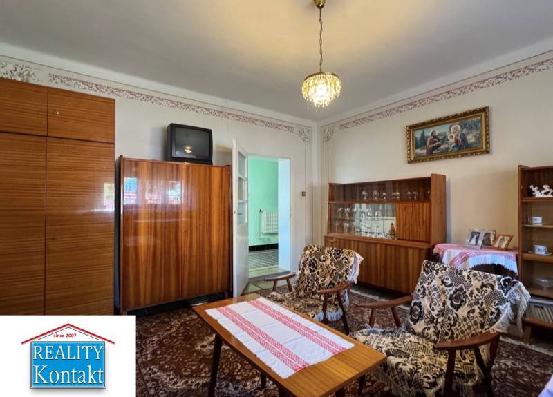 Living room in a family house with a carpet, older furniture, and a chandelier.