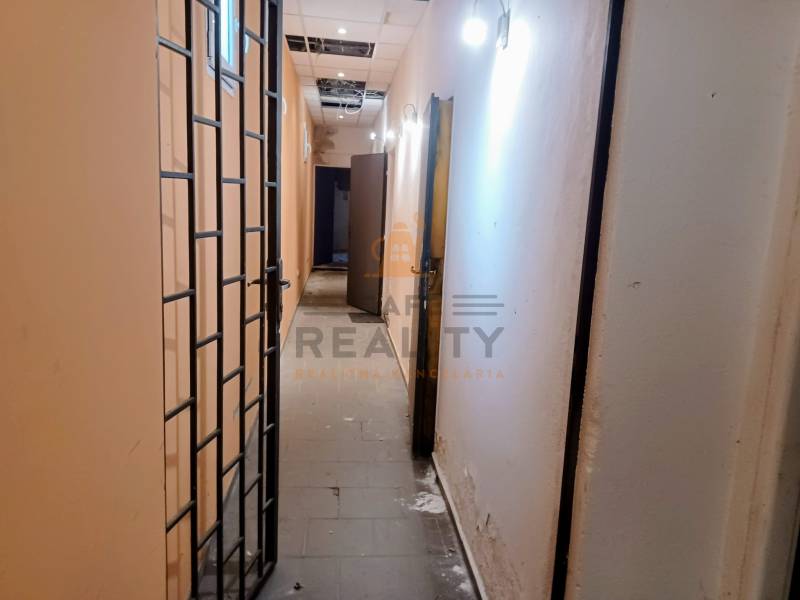 A narrow corridor with a metal grid and lighting in commercial premises.