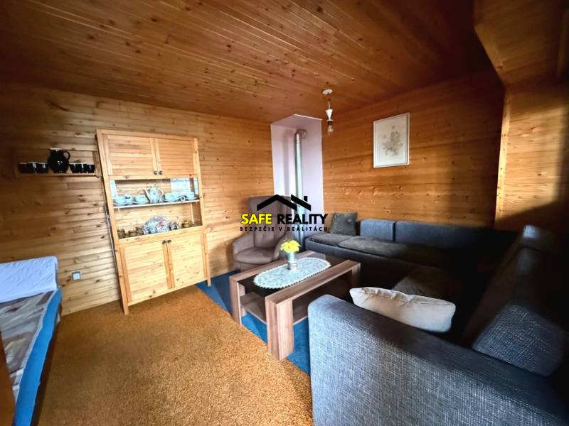 The interior of the cabin with wooden decor, comfortable sofas, and a display cabinet for dishes.