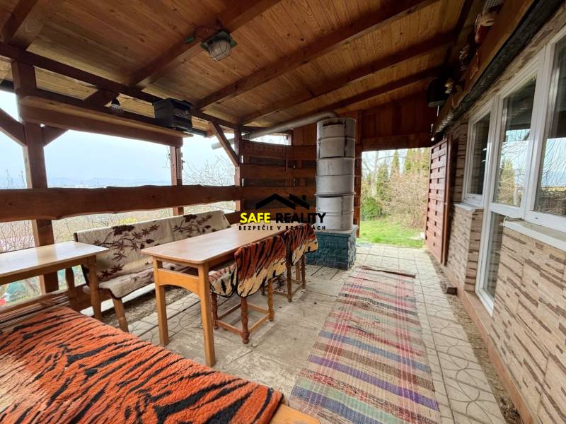 A cottage in Žilina with wooden seating, a fireplace, and a view of nature.