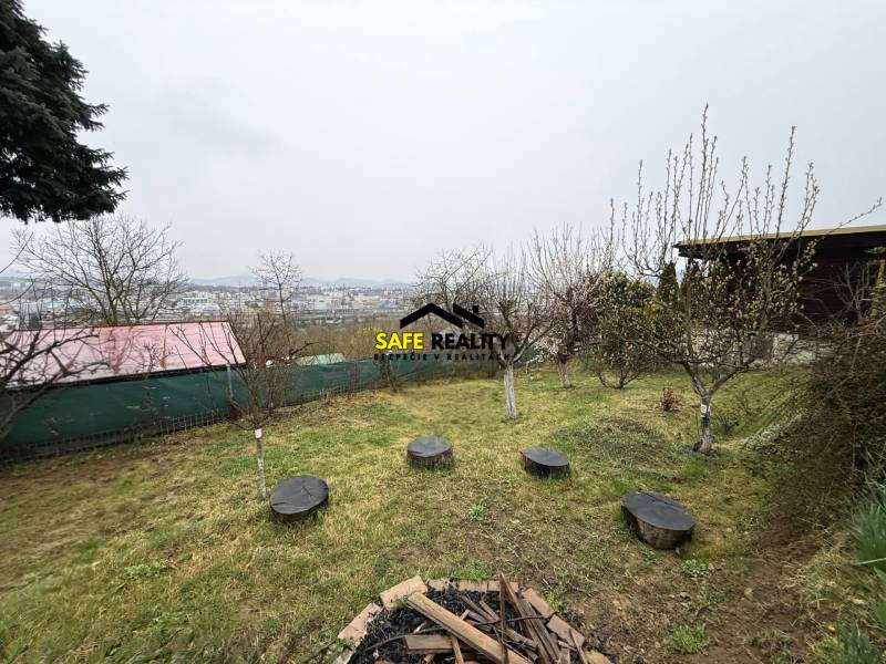 A garden by the cottage in Žilina with a view of the city and trees.