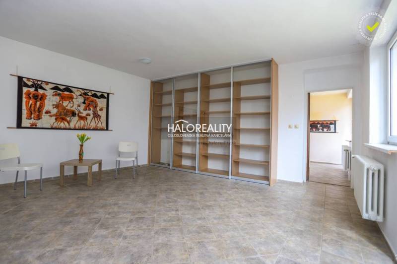 Living room with wood-patterned flooring, wall tapestry, and shelving system.