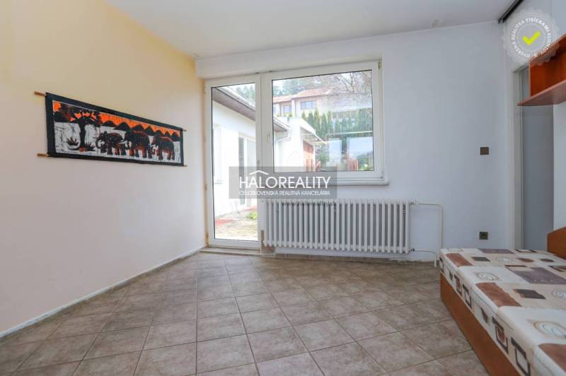 Interior of a family house with a tiled floor, a sofa, and a large window.