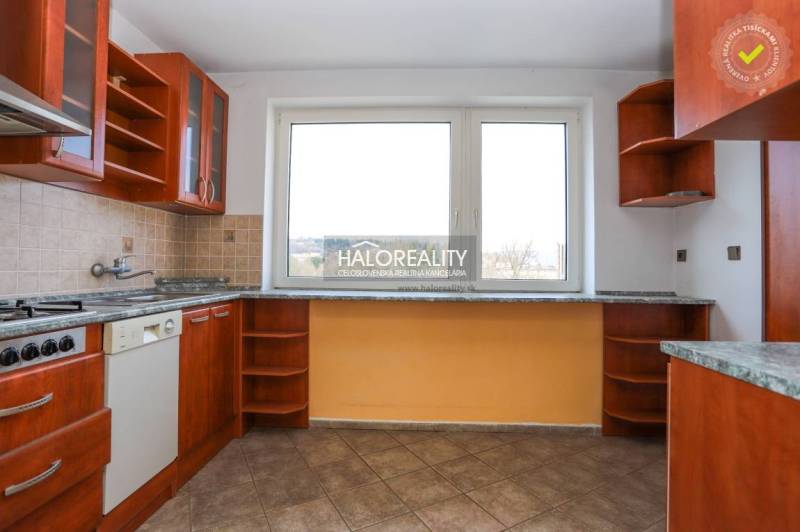 A kitchen in a family house with a kitchen unit and a large window, tiled floor.