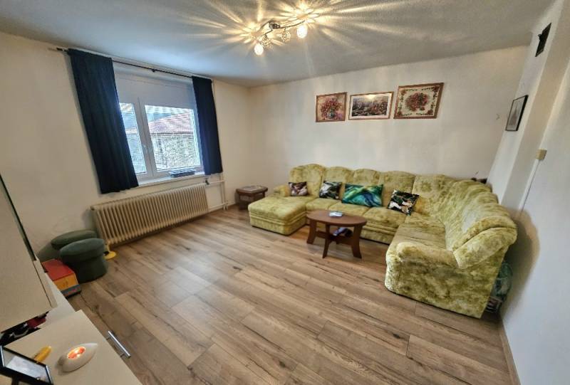 Living room in a family house with a sofa, armchairs, and a wooden decor floor.