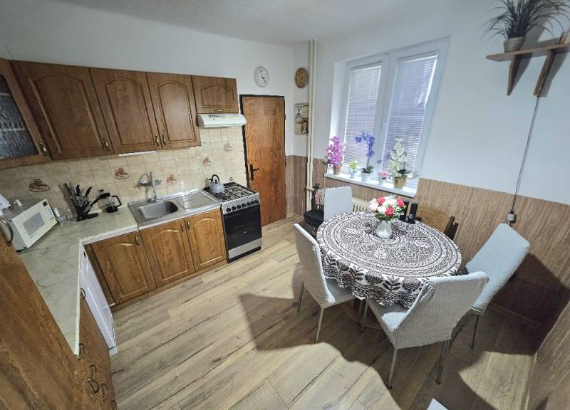A kitchen in a family house with wooden decor, with a dining table and kitchen unit.