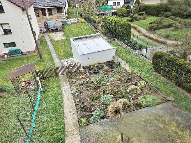 A family house in Horné Ozorovce, Bánovce nad Bebravou, features a garden with a flower bed and a garage.
