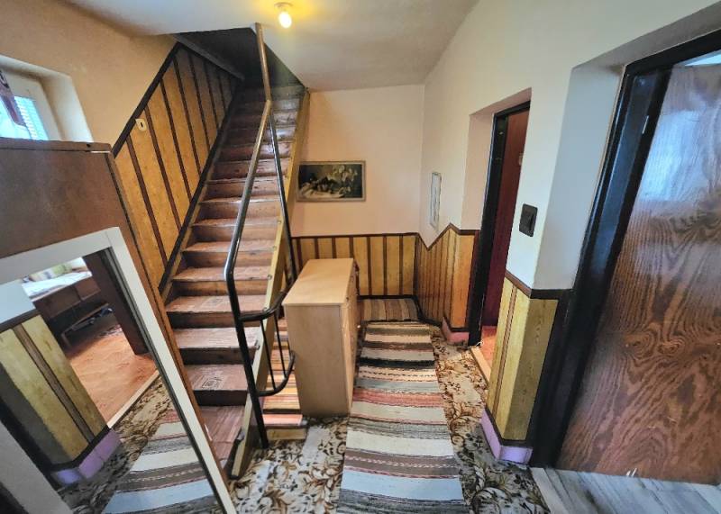 Staircase with wooden railing, carpet, and decorative wall paneling in a family house.