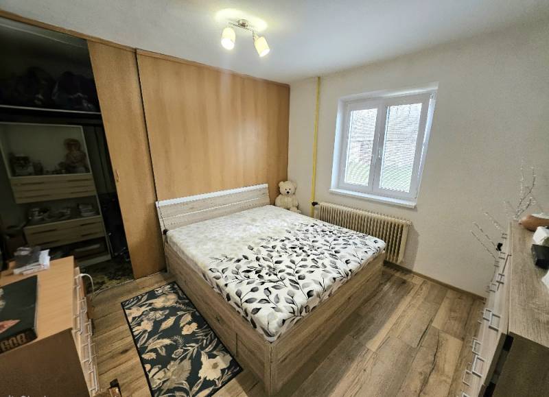 Bedroom with a bed and wooden decor flooring in a family house.