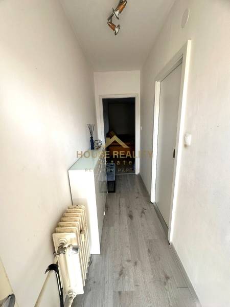 A narrow corridor with a wooden decor floor and a radiator in a 2-room apartment.