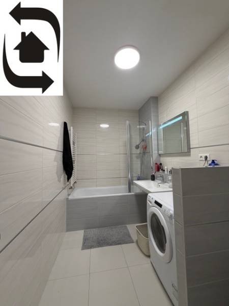 A bathroom in a 2-room apartment with a shower, bathtub, and washing machine.