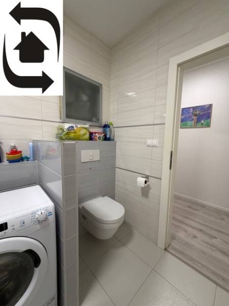 Bathroom with a washing machine, toilet, and tiles in a 2-room apartment.