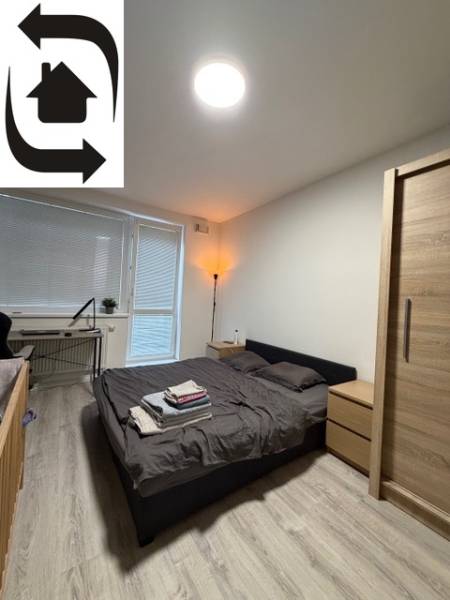 Bedroom in a 2-room apartment with a wooden decor floor and a bed next to the window.