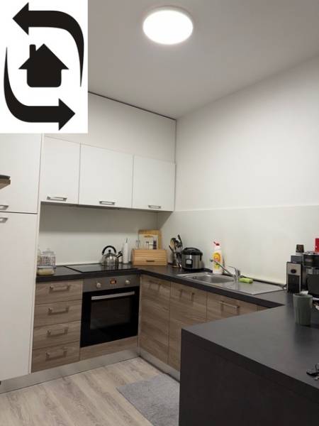 A kitchen in a 2-room apartment with a wood-patterned floor and white cabinets.