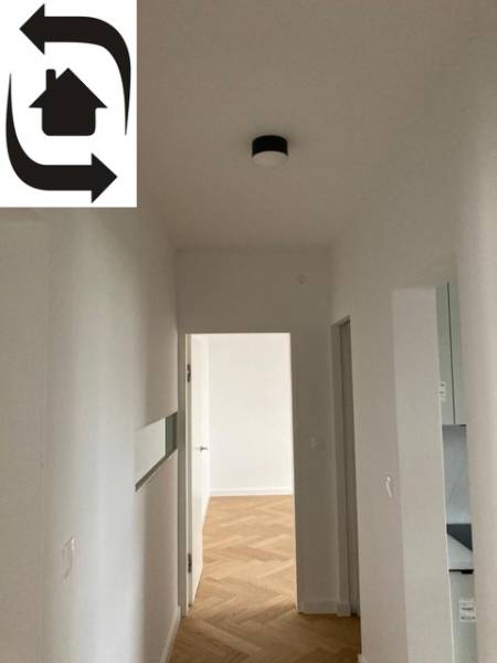 A hallway in a 2-room apartment with a wooden decor floor and white walls.