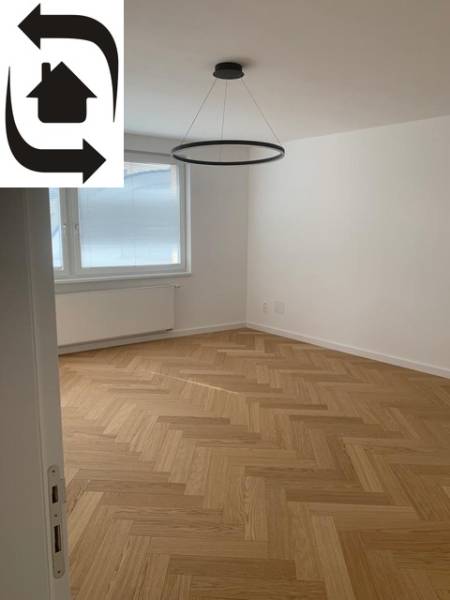 A room in a 2-room apartment with a wood-patterned floor and a window.