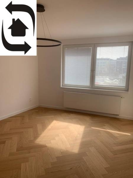 A bright room with a wood-decor floor in a two-room apartment, large window.