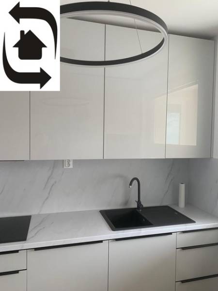 A kitchen with white cabinets and a marble countertop in a 2-room apartment.