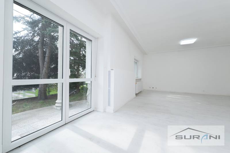 A bright room with large windows and a wooden decor floor in a 4-room apartment.