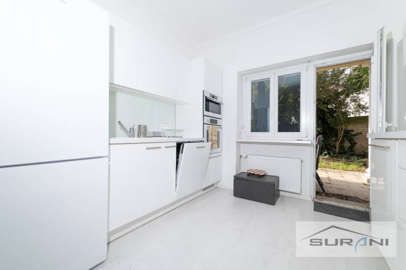 A kitchen with white cabinets and access to the terrace in a 4-room apartment.