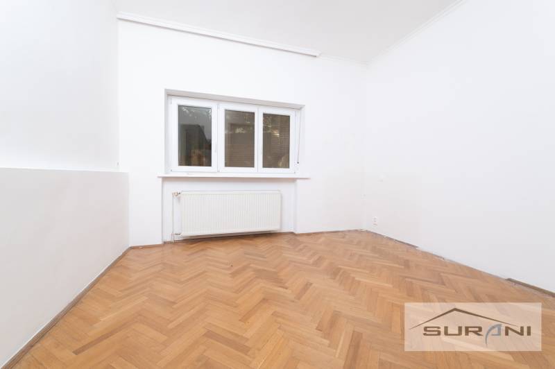 A room in a 4-room apartment with white walls and a wooden decor floor.