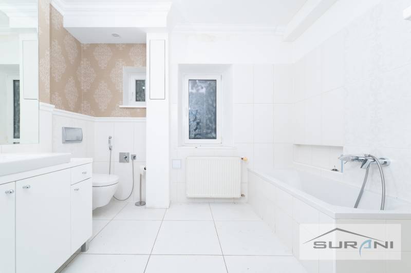 A bathroom with a shower and a bathtub in a 4-room apartment, white tiles, patterned wallpaper.