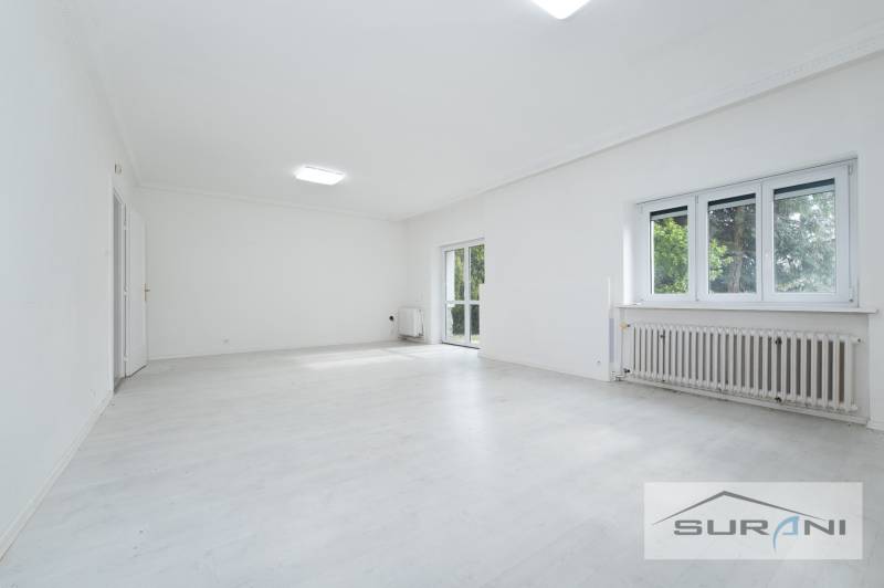 Spacious living room in a 4-room apartment with white flooring and large windows.
