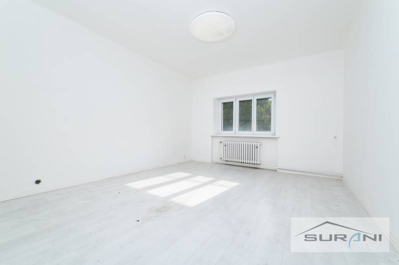An empty room with white walls and a wooden-patterned floor in a 4-room apartment.