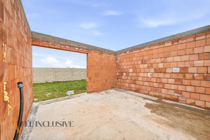 Unfinished construction of a family house in Veľké Dvorníky with a door opening and a garden.