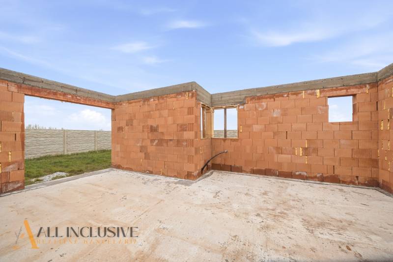 An unfinished family house in Veľké Dvorníky with bare brick walls and a concrete floor.