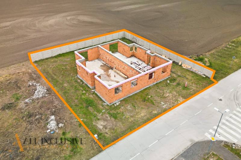 An unfinished family house in Veľké Dvorníky, outlined by an orange line, located by the road.