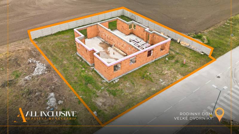 Construction of a family house in Veľké Dvorníky on a plot bordered by a fence.