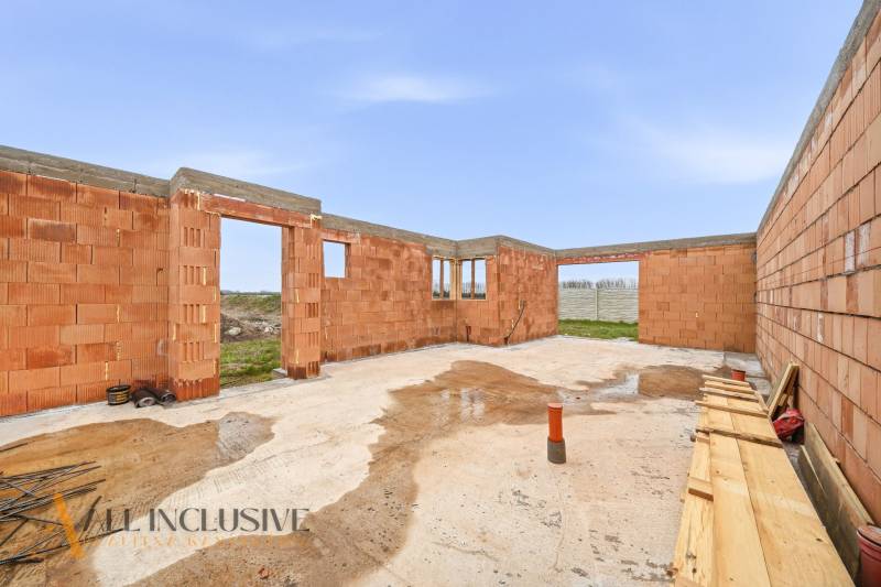 Construction phase of a family house in Veľké Dvorníky with foundations and brick walls.