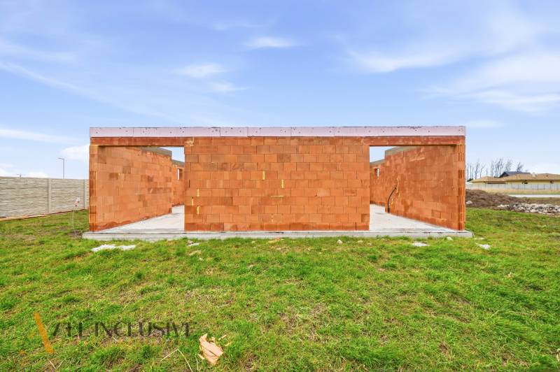 An unfinished family house in Veľké Dvorníky with brick walls and a green lawn.