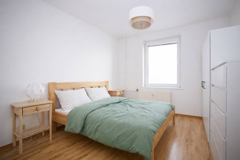 Bedroom in a 3-room apartment with a bed, nightstands, and a floor with a wooden decor.