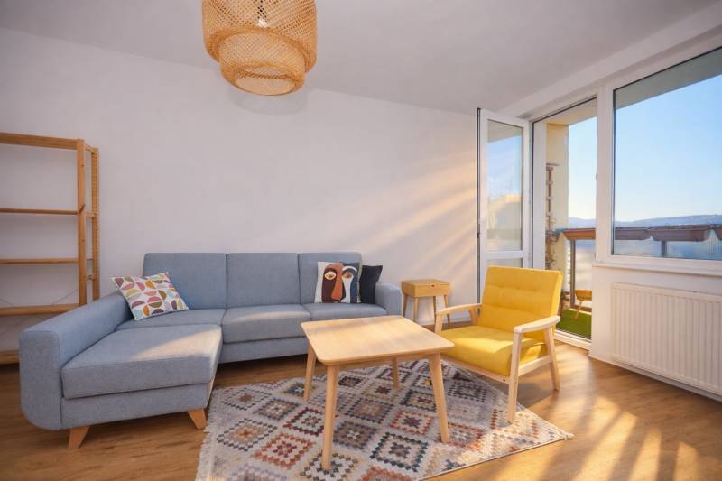 Living room with a sofa, yellow armchair, carpet, and wooden decor flooring in a 3-room apartment.