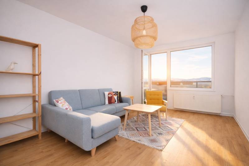 Living room of a three-room apartment with a sofa, an armchair, and a wooden decor floor.