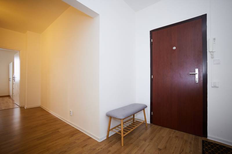Entrance hall with wood-patterned flooring and a bench in a 3-room apartment.