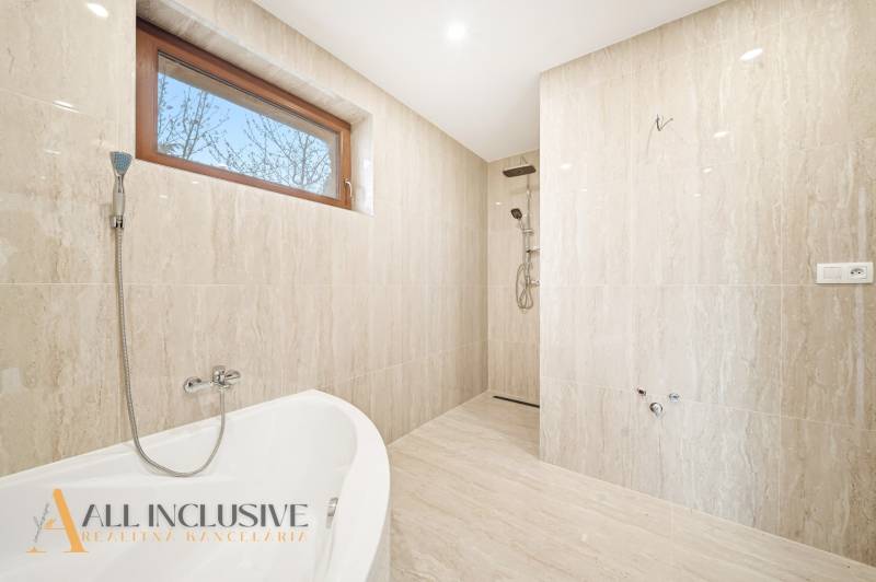A bathroom in a family house with a bathtub and a shower, the walls have a marble appearance.