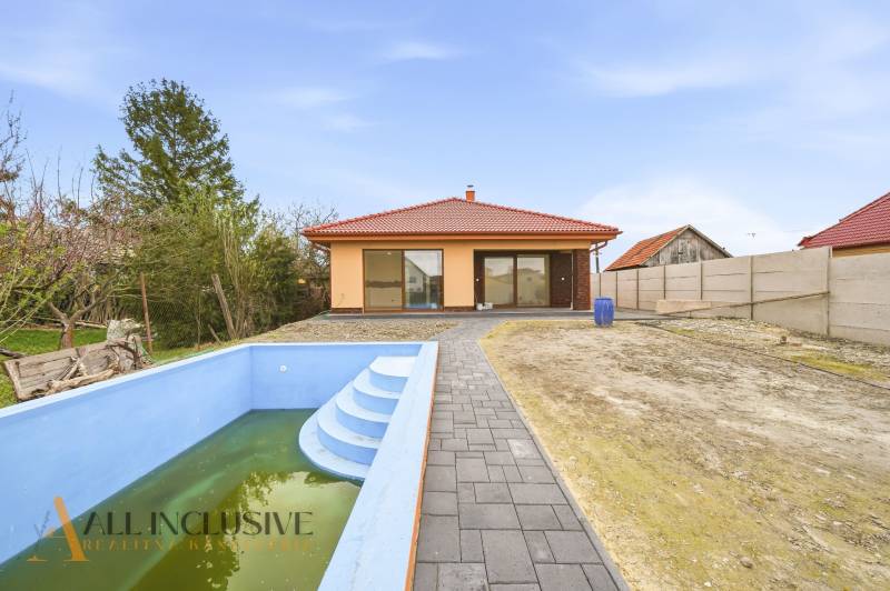 A family house in Horné Mýto with a swimming pool and a paved walkway in the garden.