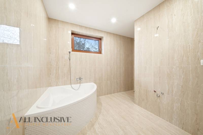 Bathroom with a bathtub and tiles in a family house. Natural tones and stylish lighting.