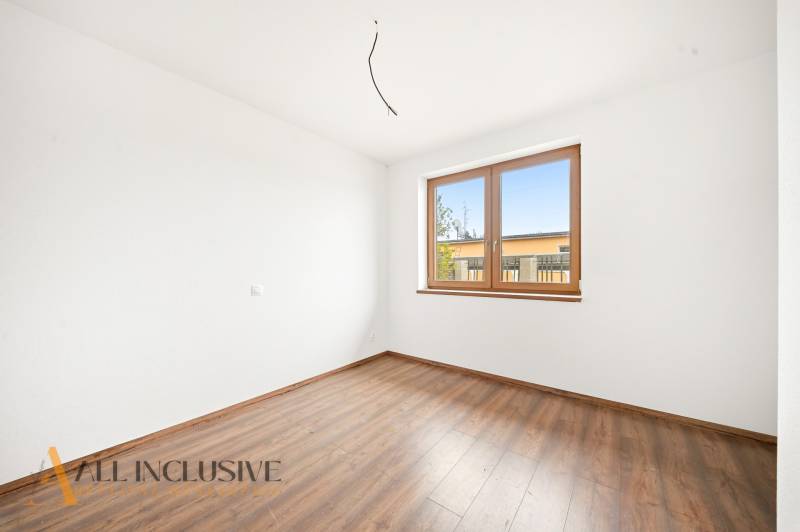 A room in a family house with a wooden decor floor and a large window.