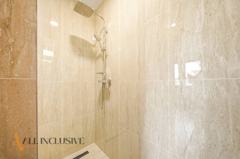 A shower enclosure in a family house with marble tiles.