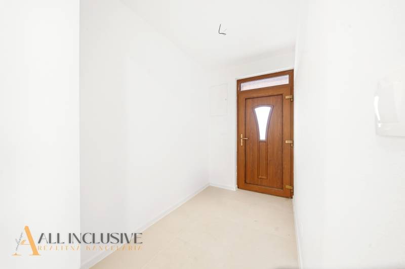 The entrance hallway of a family house with white walls and dark doors.