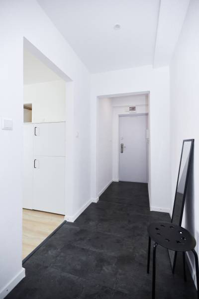 A hallway with a dark floor and white walls in a 2-room apartment.
