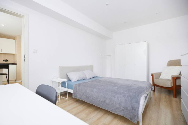 Bedroom of a two-room apartment with a bed, wardrobe, and floor with a wooden decor.